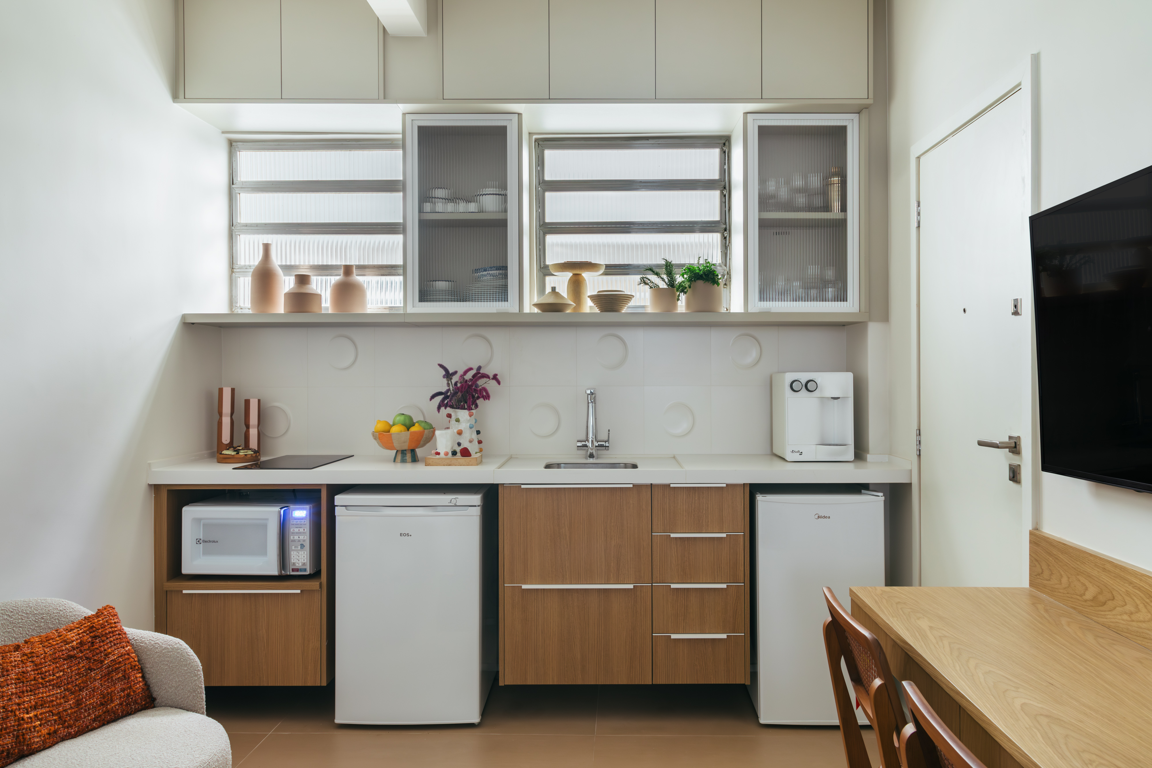 Loft de 30 m² é projetado para administradora de 80 anos que mora sozinha. Projeto de Richard de Mattos, da Casa Cururu. Na foto, cozinha com armários de madeira e tampo branco.